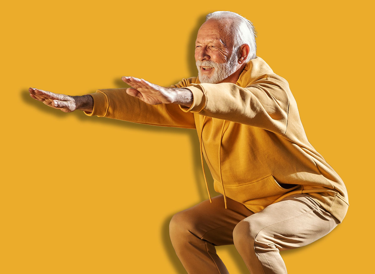 Full length of senior active sporty man in tracksuit doing squats in nature during his fitness day.